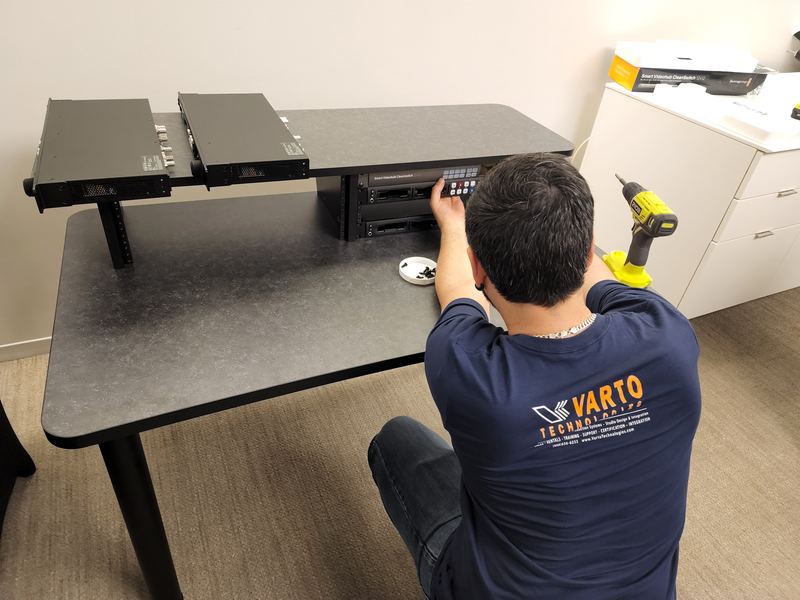 A Varto technician in a company shirt assembling rack equipment during an on-site installation