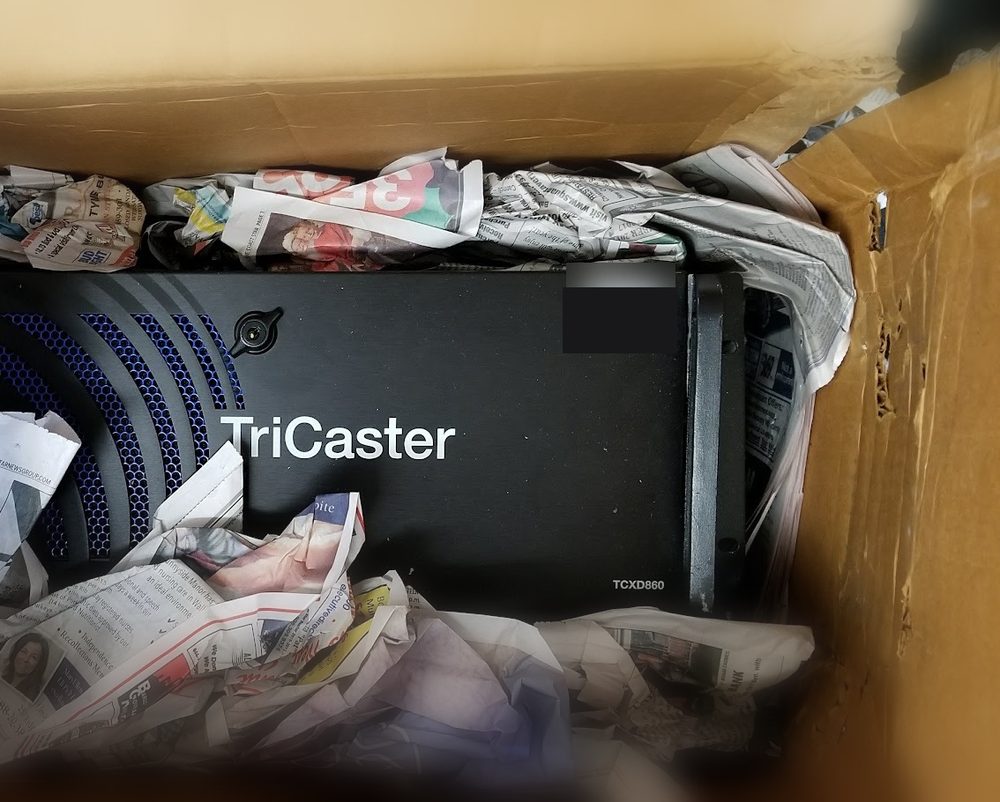 A TriCaster loose in a carton packed with crumpled newspaper