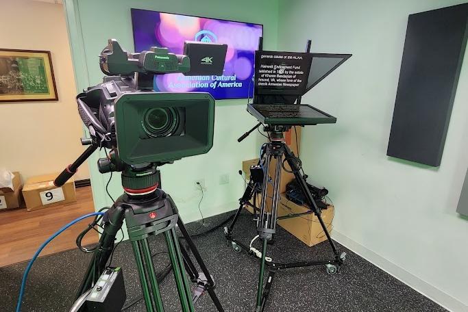 A camera and teleprompter rigged on tripods in a studio Varto built