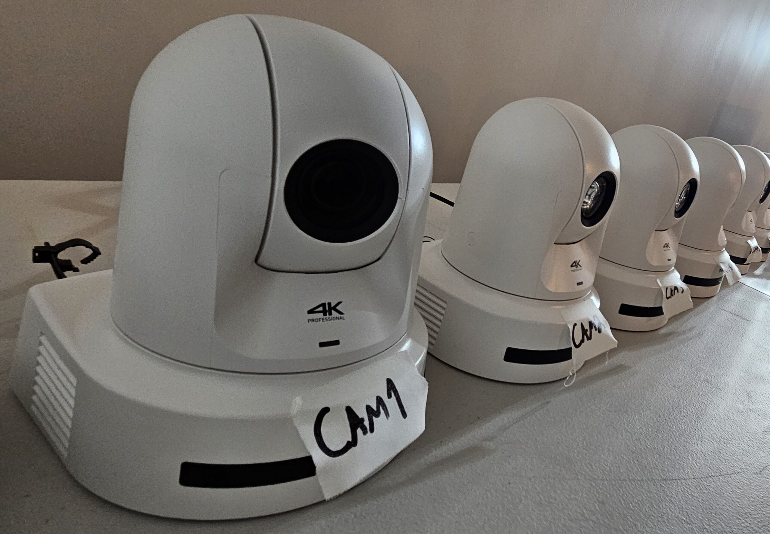 Six Panasonic 4K PTZ cameras on a work table at Varto, each hand labeled CAM 1 to CAM 6 before installation