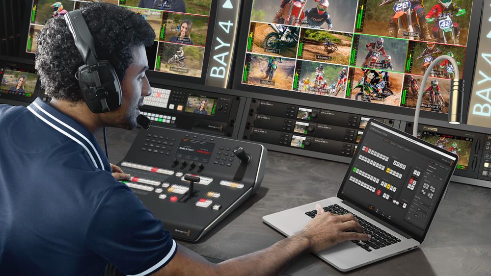 Operator at an ATEM Television Studio panel with ATEM Software Control open on a laptop beside it