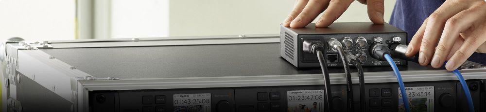 Hands connecting a Blackmagic converter on top of an equipment rack