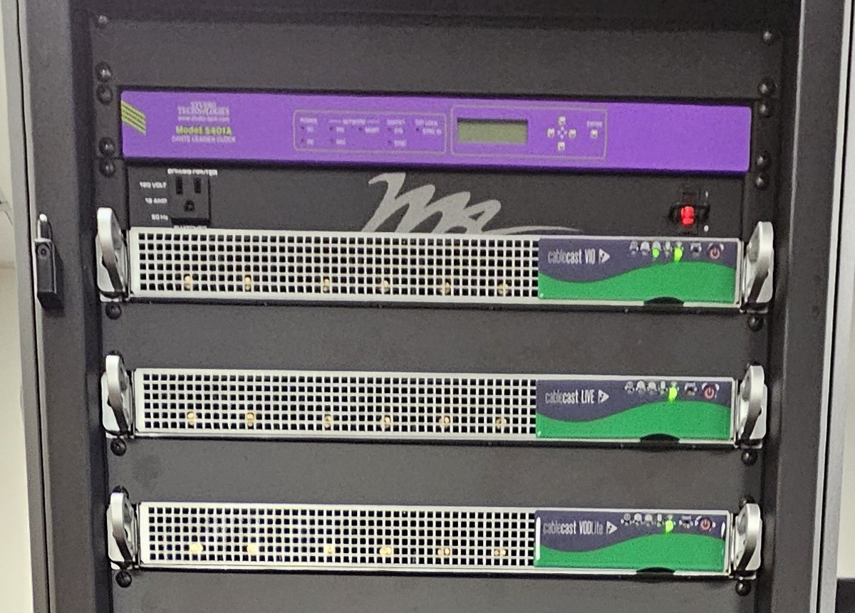 Top of an equipment rack with three Cablecast units under a Dante clock and a power conditioner