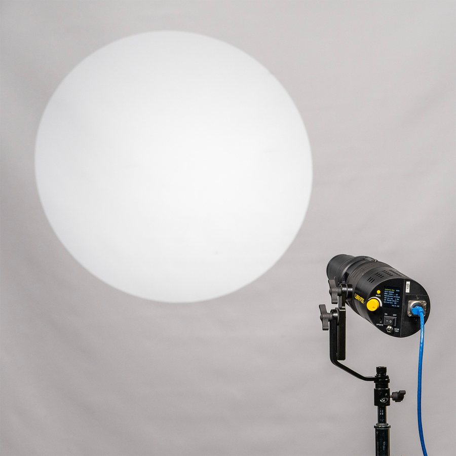 Ikan Lyra PoE ellipsoidal fixture on a stand projecting a sharp circle of light onto a wall