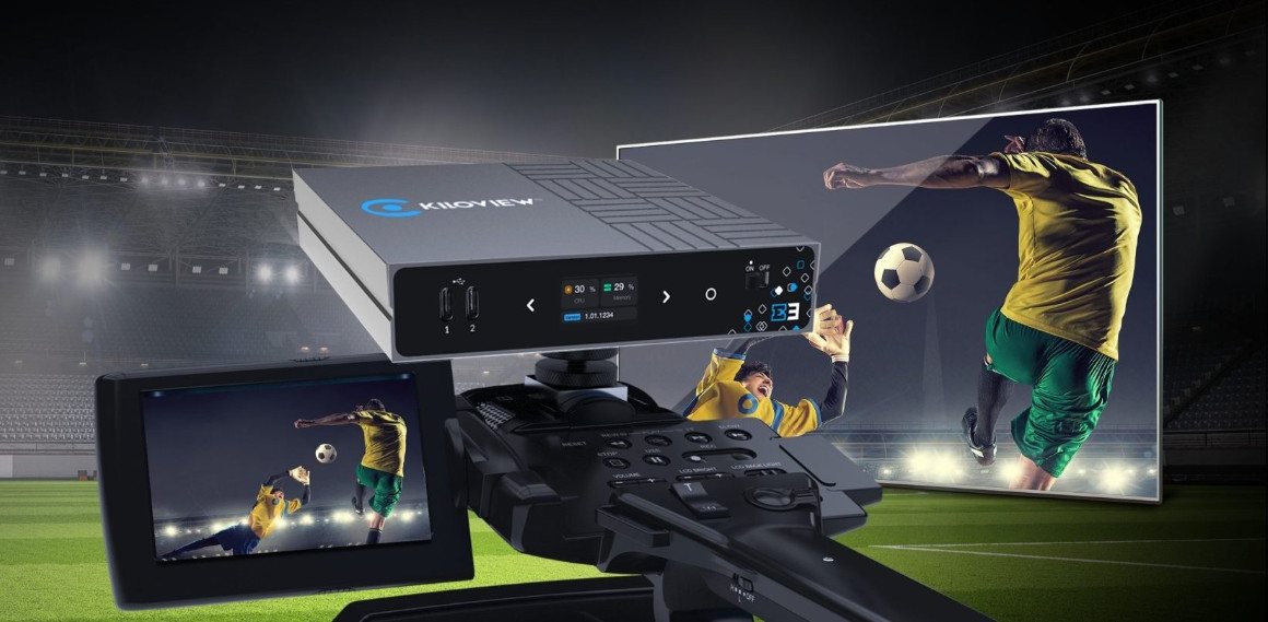 Kiloview E3 encoder on a camera rig beside a monitor showing a soccer match, with a stadium behind