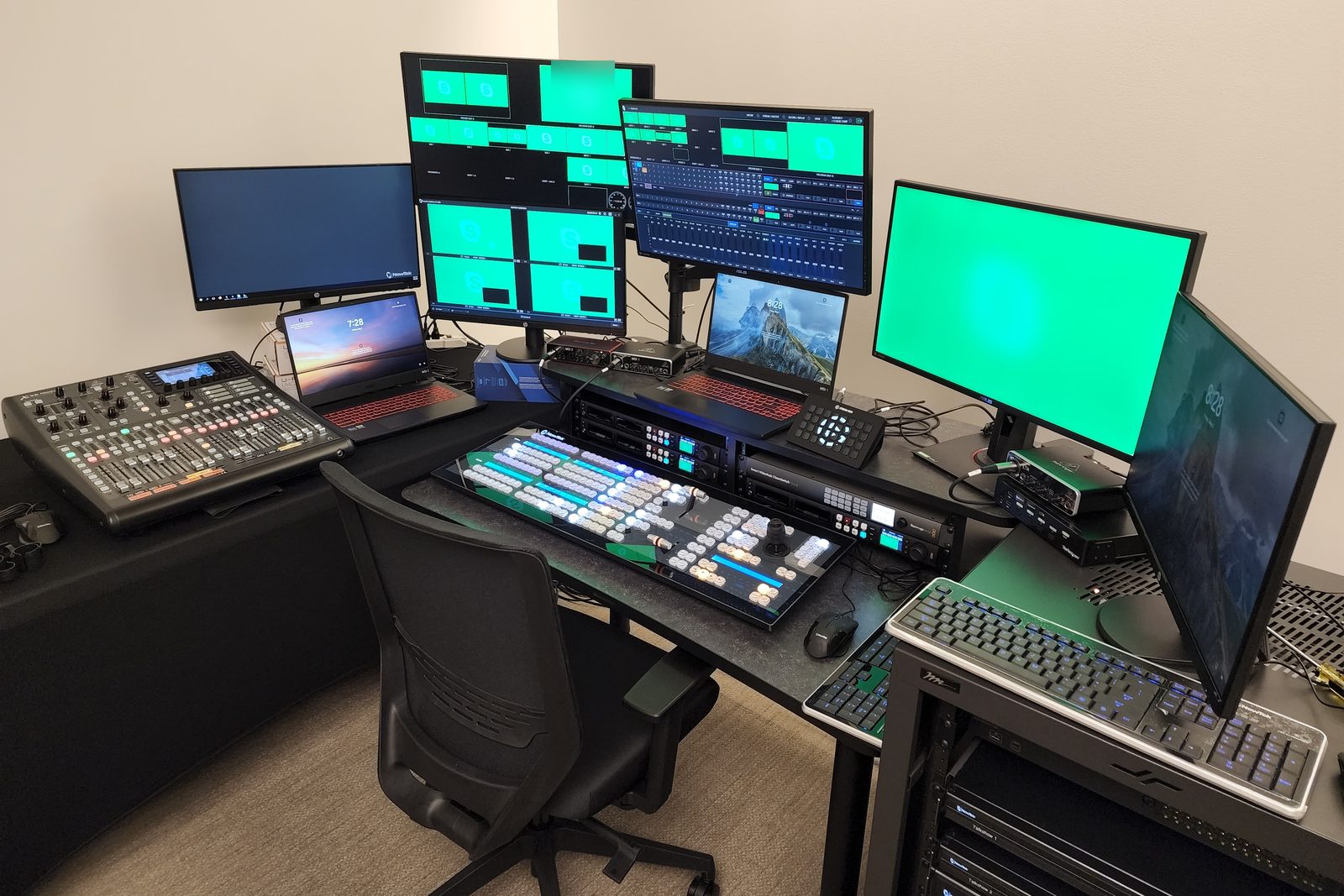 Production position at The Washington Post: a TriCaster two-stripe control surface on the desk with an audio console, laptops, a multiviewer and program monitors