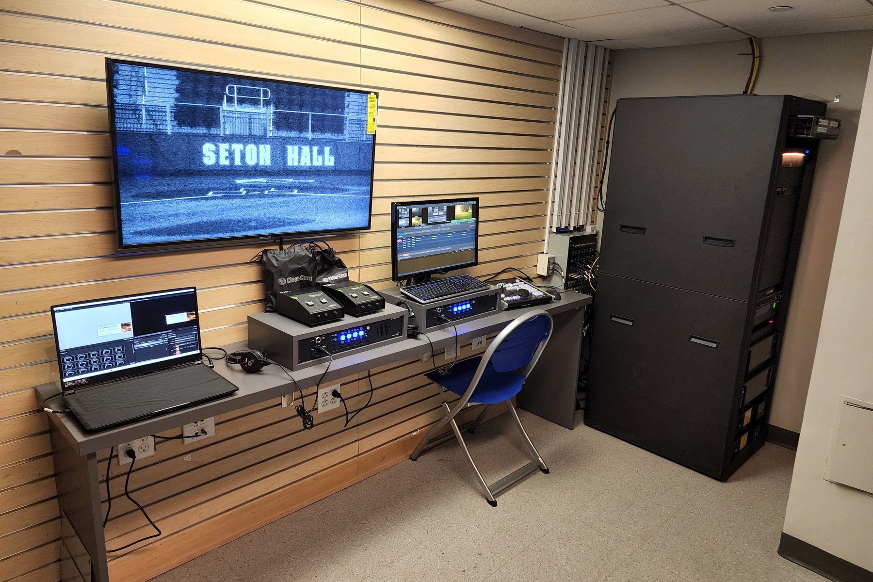 Seton Hall Athletics control room, wall monitor carrying the Seton Hall broadcast graphic above the switcher and replay positions