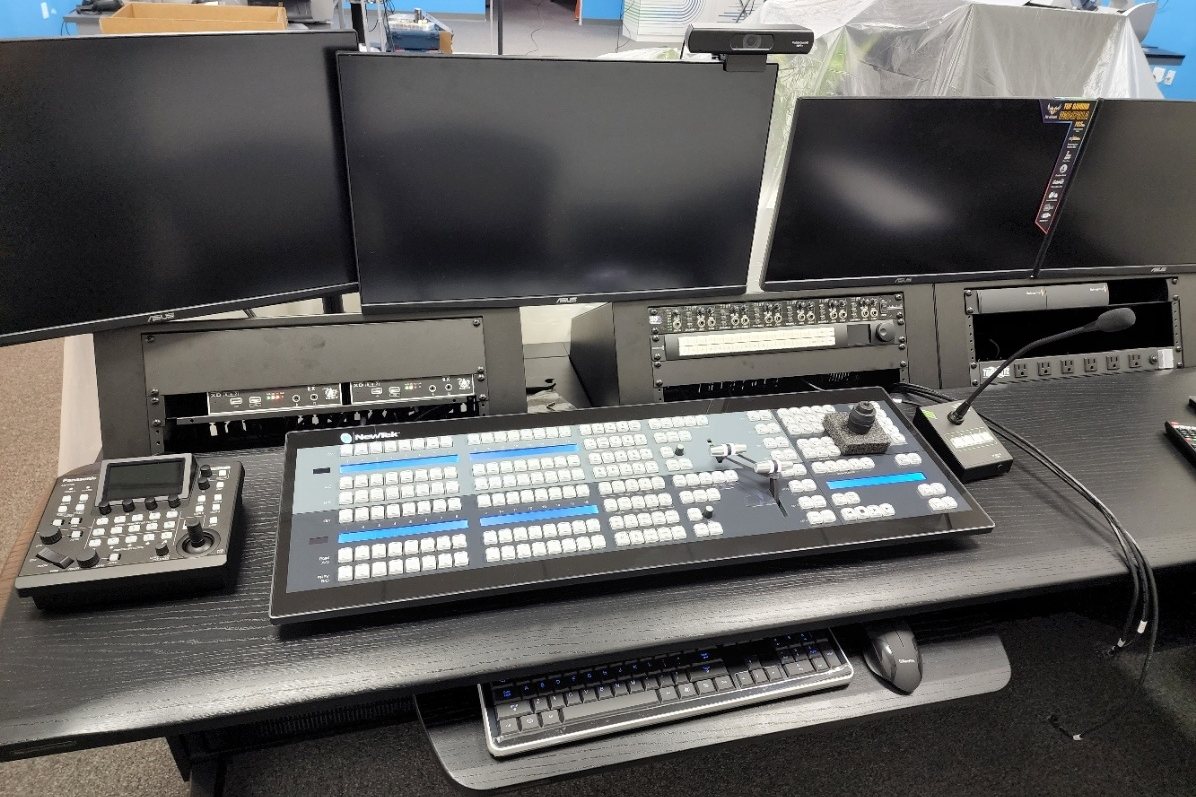 Production desk with a switcher control panel, a PTZ camera controller and three monitors