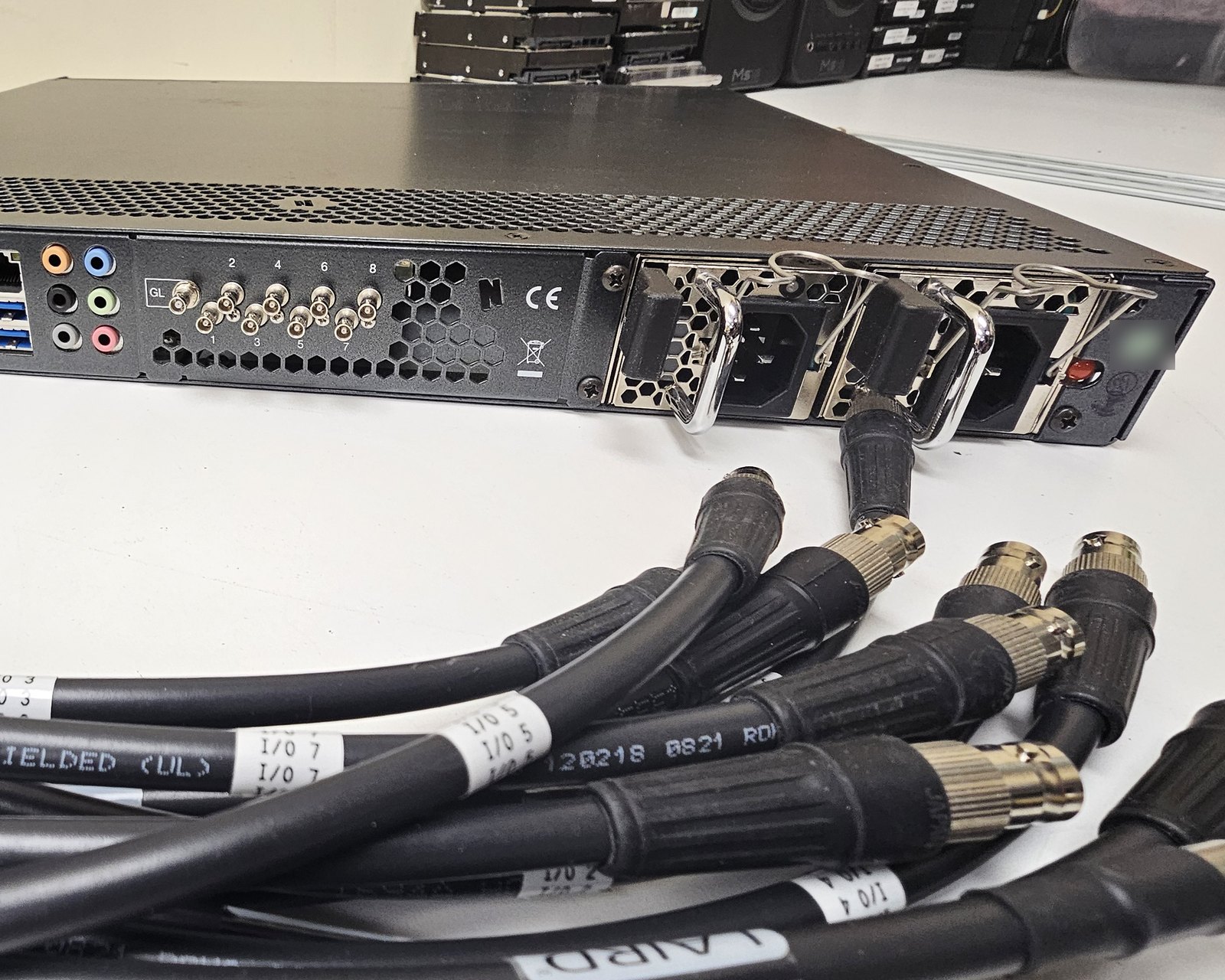 The rear panel of a NewTek 1RU I/O unit on the Varto repair bench, its SDI connectors wired to labeled test cables