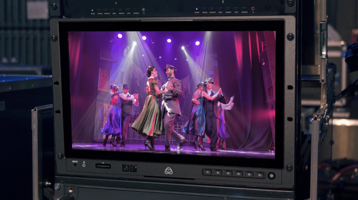 An Atomos Shogun AV-19 mounted in a road rack below two rack units, its screen showing a dance performance on a lit stage