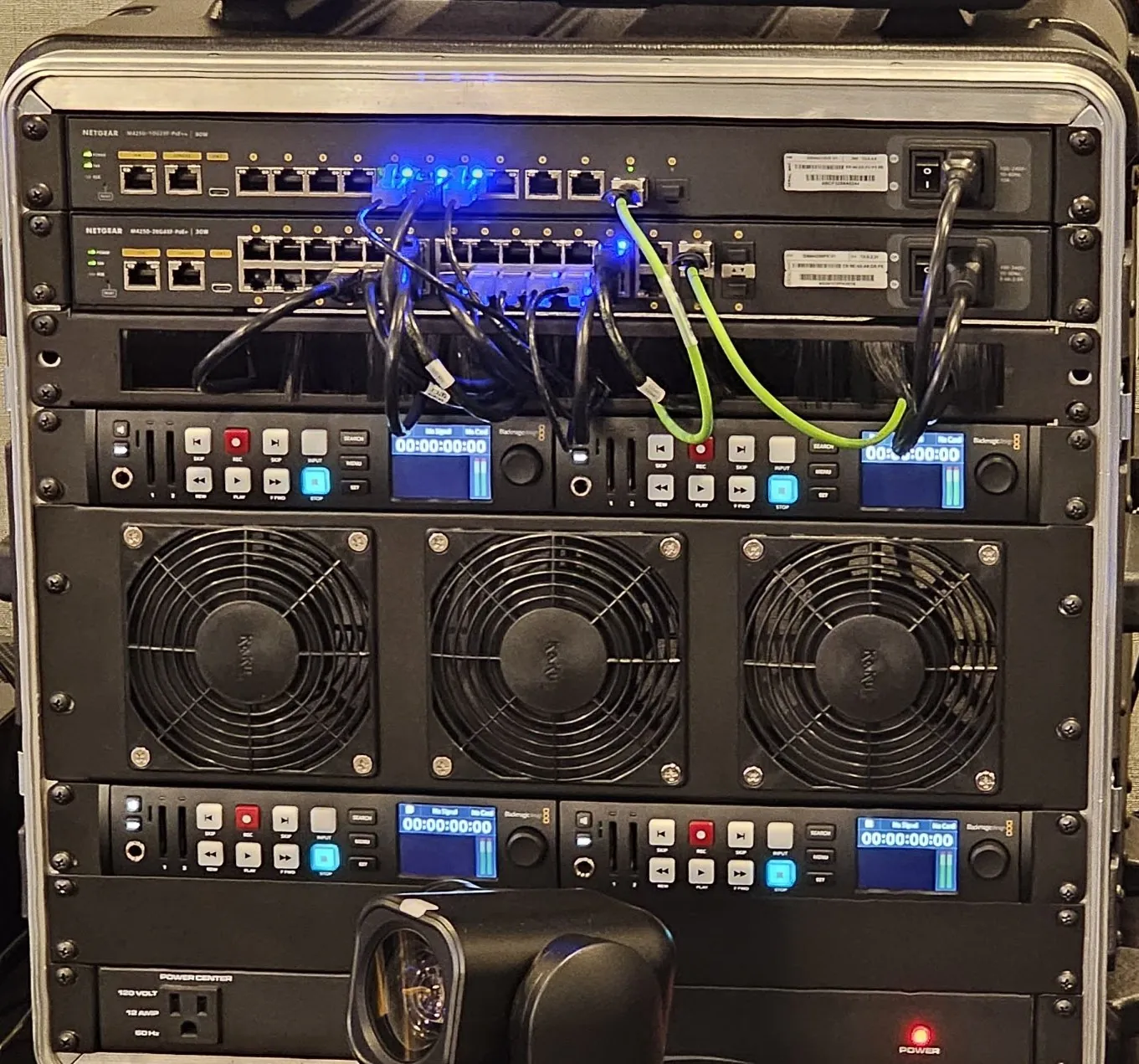 Two NETGEAR M4250 switches mounted above four Blackmagic HyperDeck recorders in a portable rack