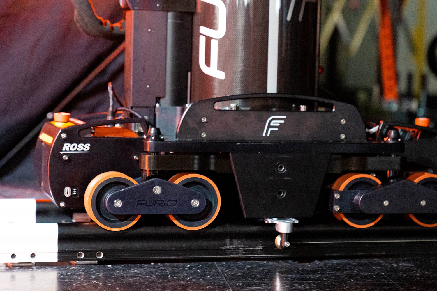 Close-up of a Furio robotic camera dolly with orange wheels on its track