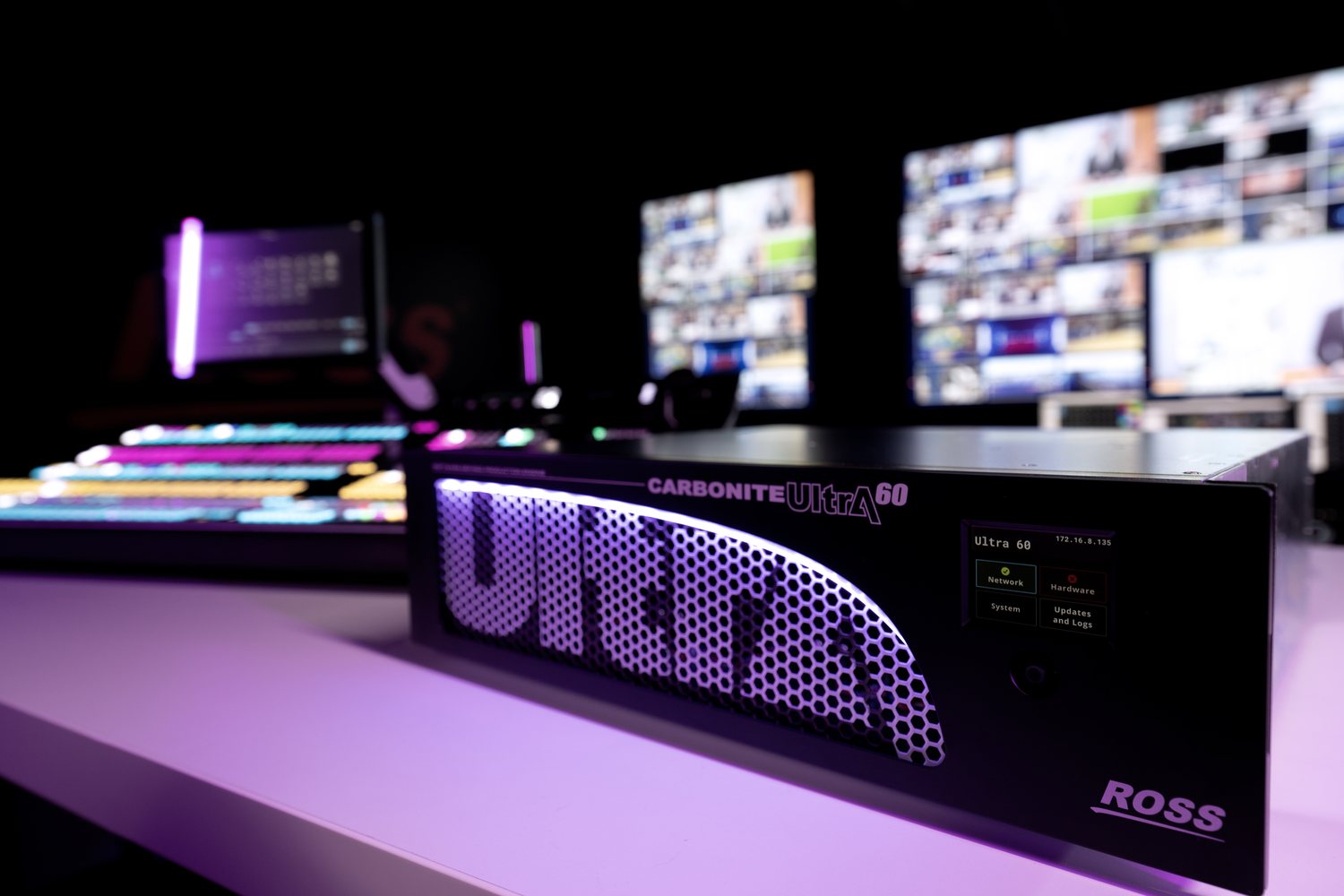 A Carbonite Ultra 60 frame lit purple on a desk, with a TouchDrive panel and monitor walls out of focus behind it